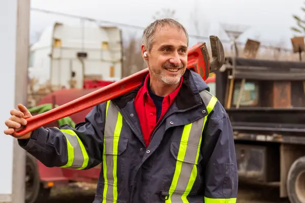 Mr. Rooter professional outdoors with a large wrench.