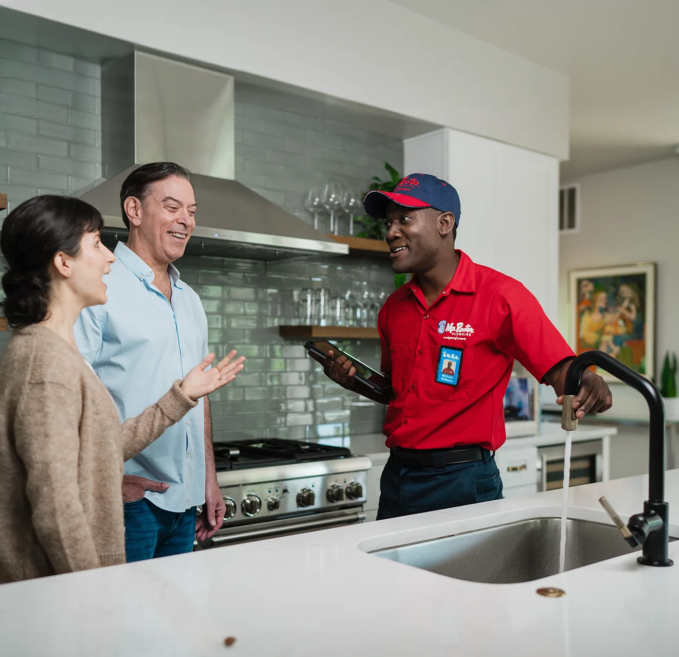 Mr. Rooter technician explaining to two customers how their water filter works.