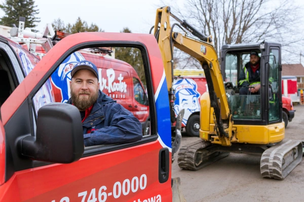 Mr. Rooter technician standing behind the open door of a branded vehicle.