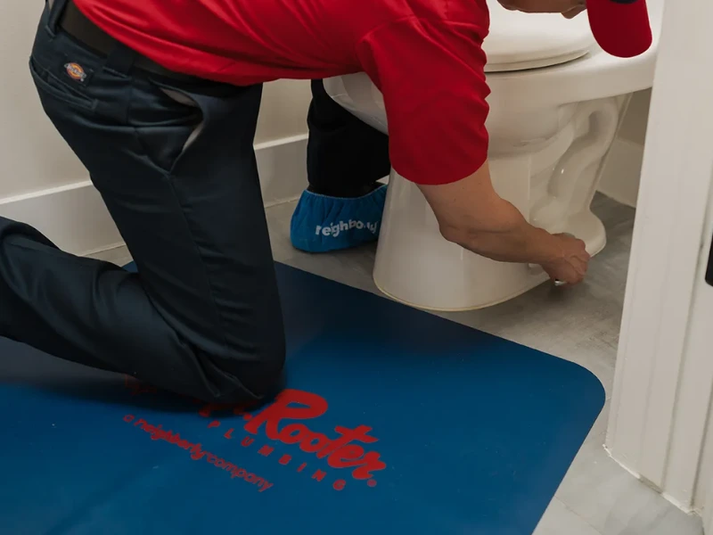 Mr. Rooter professional fixing a toilet.