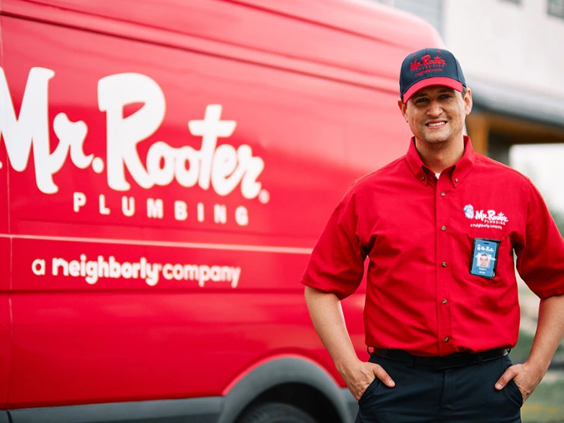 Mr. Rooter employee standing by red Mr. Rooter van.
