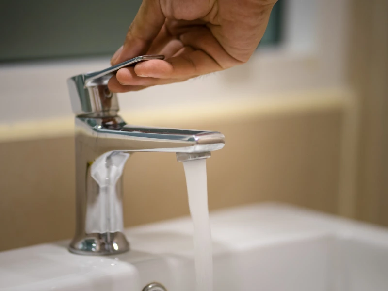 A person turning on a bathroom faucet.