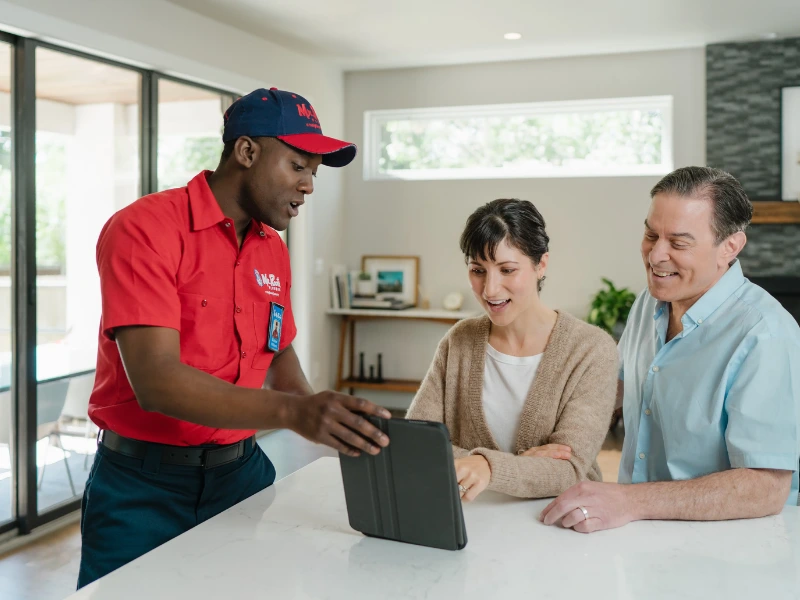 Mr. Rooter professionals speaking with a customer and showing them something on a tablet screen.