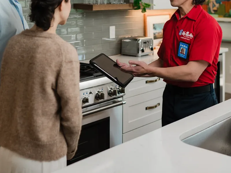 Mr. Rooter professional showing a customer something on a tablet.