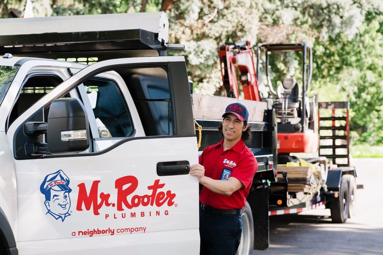 A Mr. Rooter proffesional in uniform walking up to a customer's home